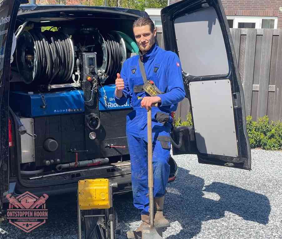 Een monteur bij de werkbus met grote hogedruk-slanghaspels, apparatuur voor hardnekkige afvoerverstoppingen in Hoorn