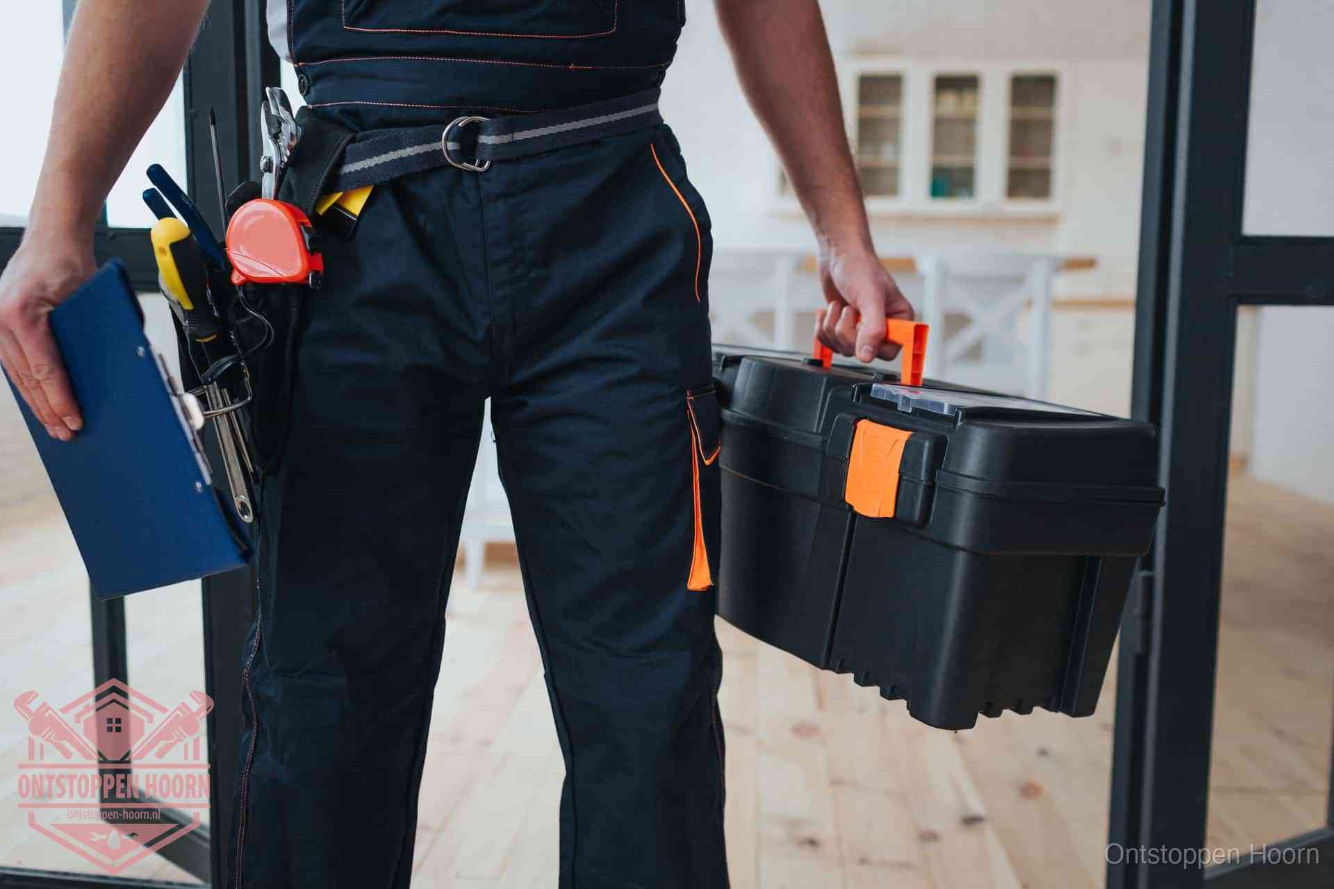 Een monteur met gereedschapsriem en klembord in een keuken, klaar om een transparante prijs voor het gootsteen ontstoppen in Hoorn te geven