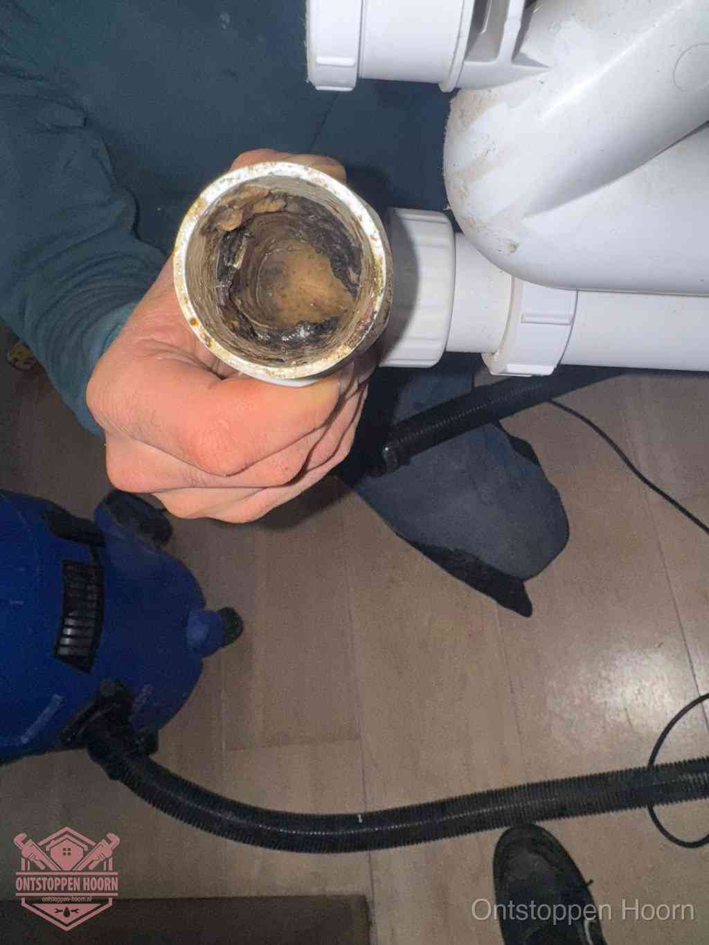 Een losgekoppelde afvoerbuis die van binnen volledig is dichtgeslibd met vet en aanslag, de meest voorkomende oorzaak van een verstopte gootsteen in Hoorn