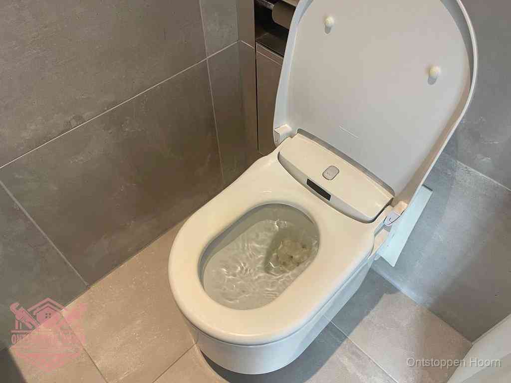 Een toiletpot vol troebel water met drijvend papier en restanten, de meest voorkomende oorzaak van een verstopte wc in Hoorn