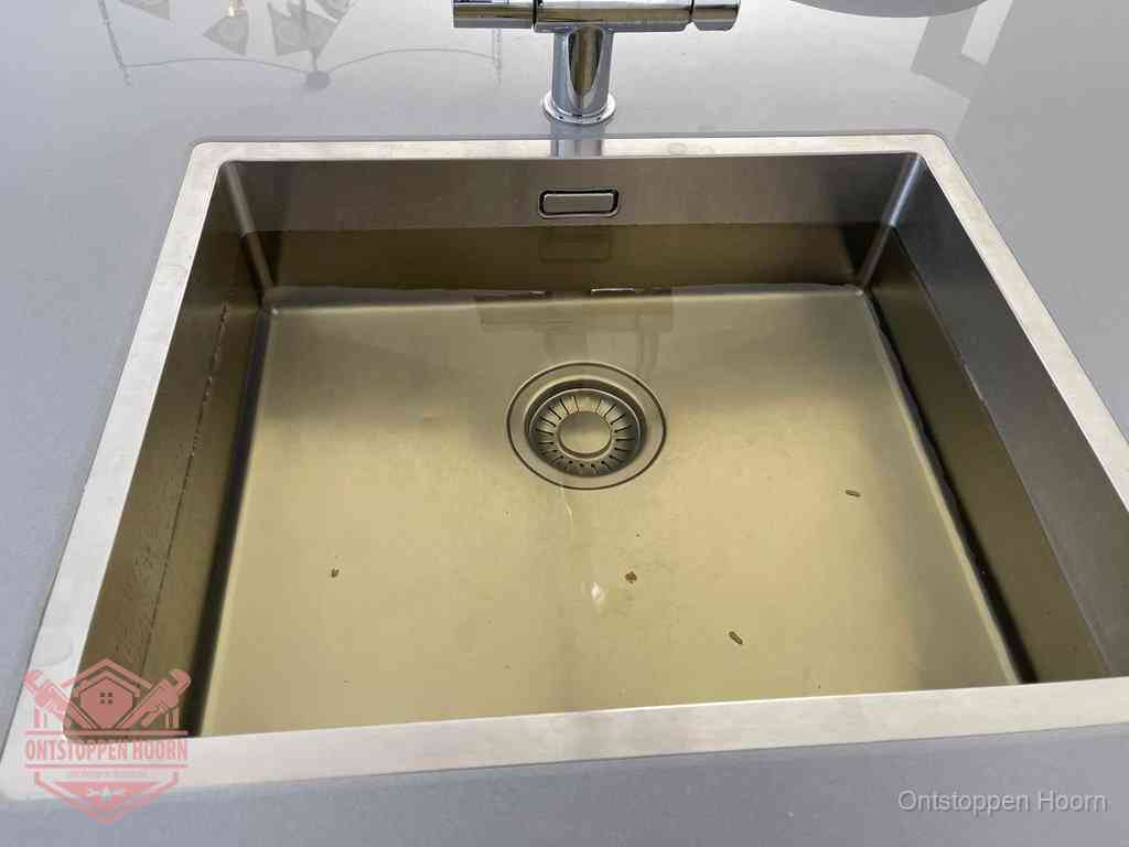 Stilstaand water in een rvs spoelbak dat niet wegloopt, een duidelijk signaal van een gootsteenverstopping in Hoorn