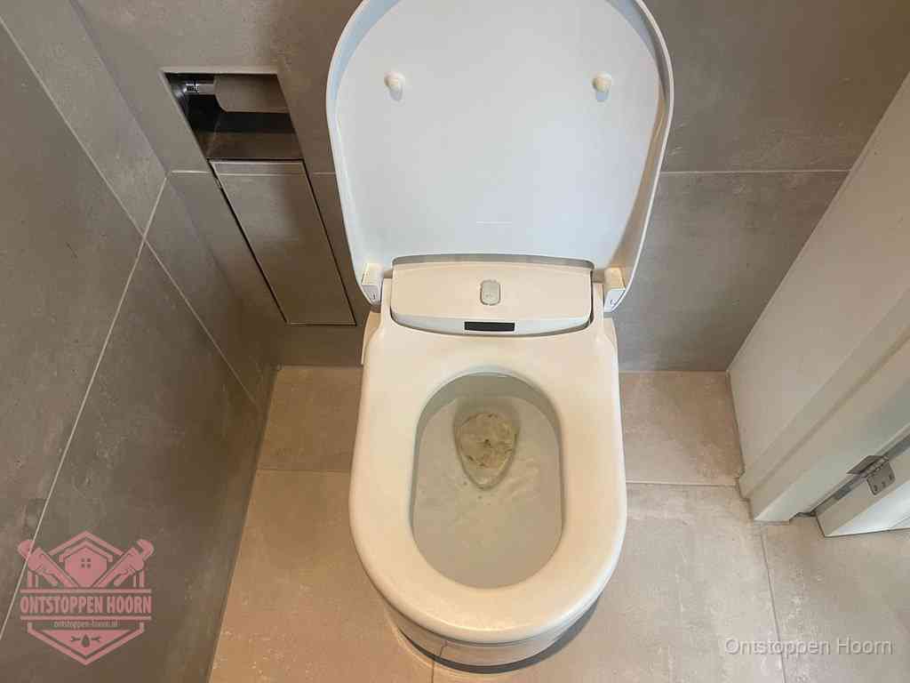 Een wit hangtoilet waarin een prop wc-papier op het water blijft drijven, een duidelijk signaal van een verstopte wc in Hoorn