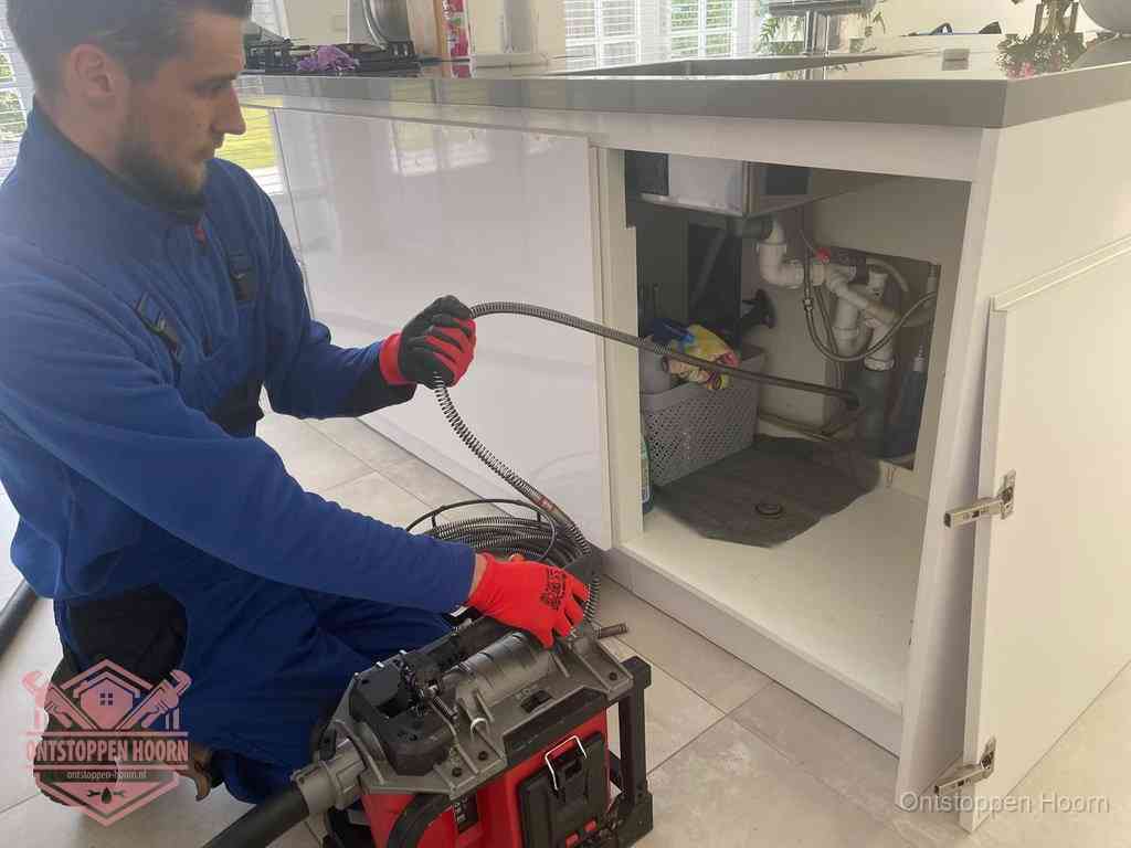 Een monteur reinigt de keukenafvoer grondig met een veermachine om terugkerende gootsteenverstoppingen te voorkomen in Hoorn
