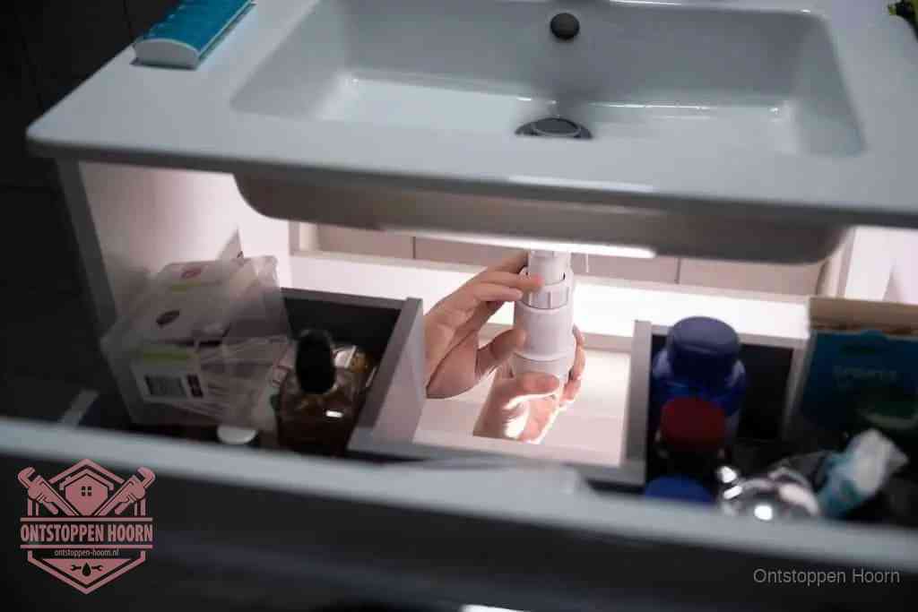 Een pompfles met zeep boven een wastafel in de toiletruimte, de warm water en afwasmiddel-methode om de wc te ontstoppen in Hoorn